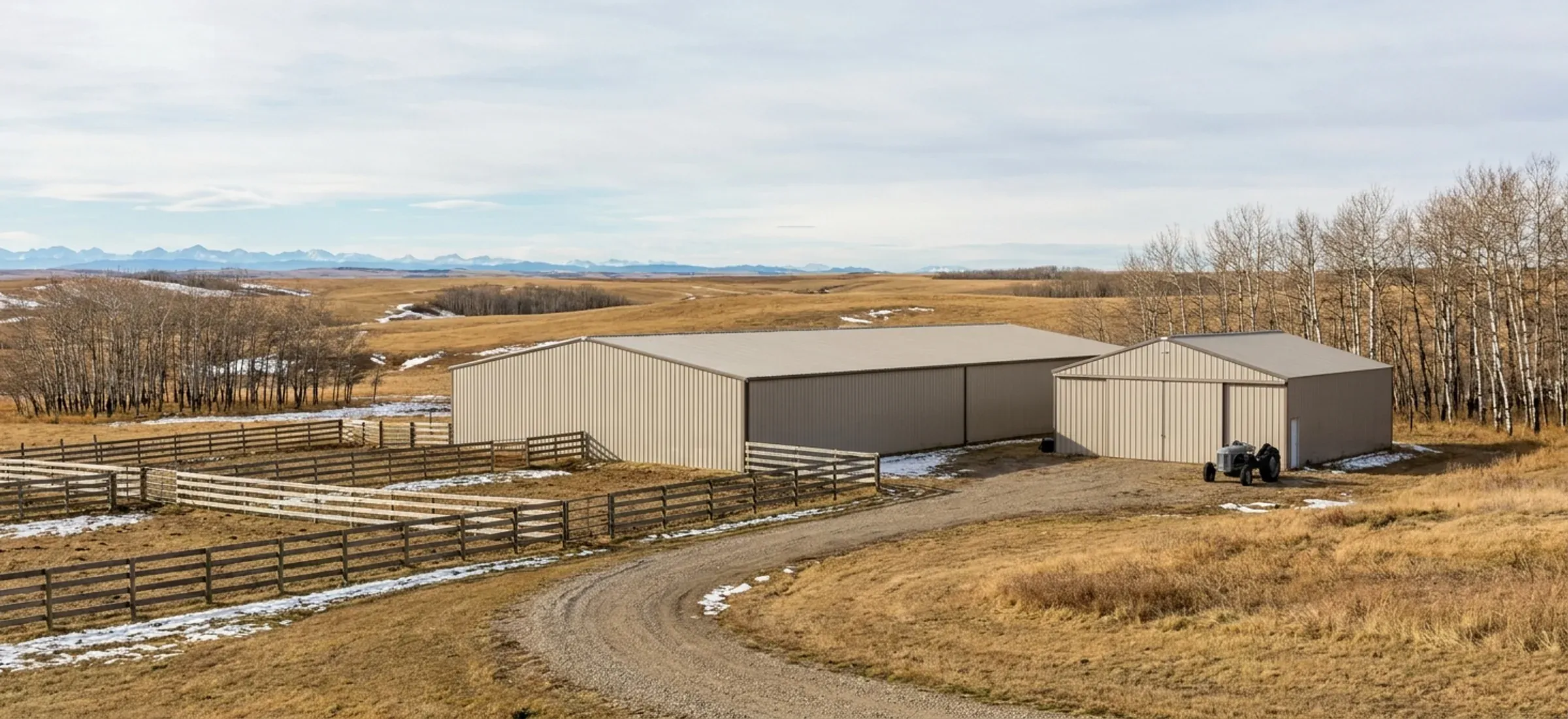 A long steel riding arena beside paddocks and a small barn on rolling acreage land